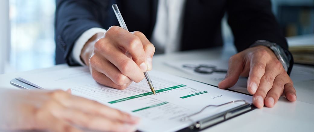 Man filling out paperwork at his desk.
